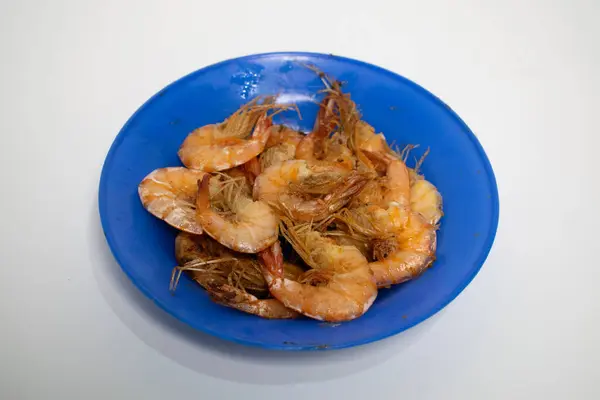 Canlı bir mavi tabakta servis edilen kızarmış karides, tadını çıkarmaya hazır..