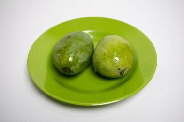Bir çift parlak yeşil mango yeşil bir tabakta yan yana konur..