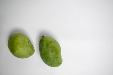 Temiz beyaz bir zemine yerleştirilmiş iki yeşil mango, minimum ve taze bir görünüm yaratıyor..