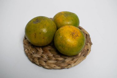 Yeşilimsi sarı derili üç olgun portakal bir tabakta güzelce sıralanır..