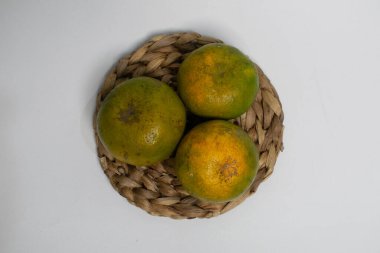 Doğal lekeli organik portakallar kırsal bir hasırın üzerine konur..