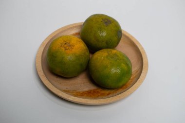 Basit bir ahşap tabakta sunulmaya hazır üç taze portakal..