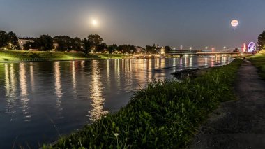 Dolunayda Krakow 'daki Vistula Nehri' nin üzerindeki gece ışıkları..