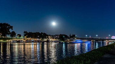 Dolunayda Krakow 'daki Vistula Nehri' nin üzerindeki gece ışıkları..