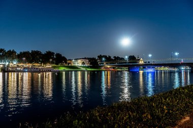 Dolunayda Krakow 'daki Vistula Nehri' nin üzerindeki gece ışıkları..
