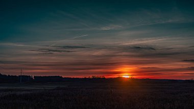 Podlasie 'de ağaçların arasından görünen sonbahar günbatımı.