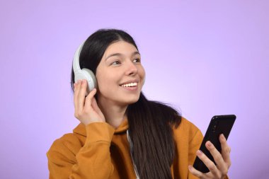 Genç ve güzel bir kadın kulaklıkla müzik dinliyor.