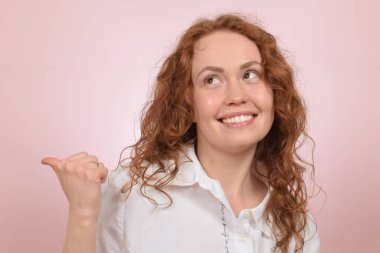 Güzel kızıl saçlı kıvırcık kadın parmağıyla yön gösteriyor.