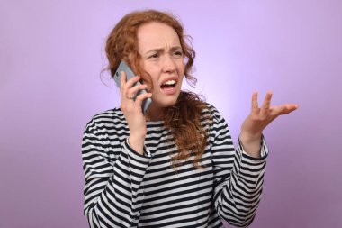 Üzgün, kızıl saçlı, telefonda duygusal konuşan kıvırcık kadın.