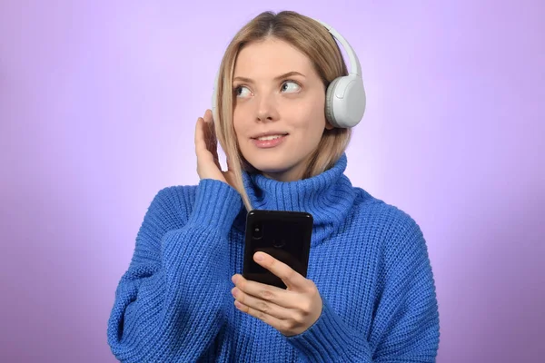 可爱的年轻女人拿着电话 用耳机听音乐 — 图库照片