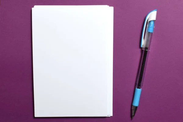 stack of white paper with a pen on a purple background