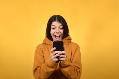 Mutlu genç esmer kadın akıllı telefondan online alışveriş yapıyor.