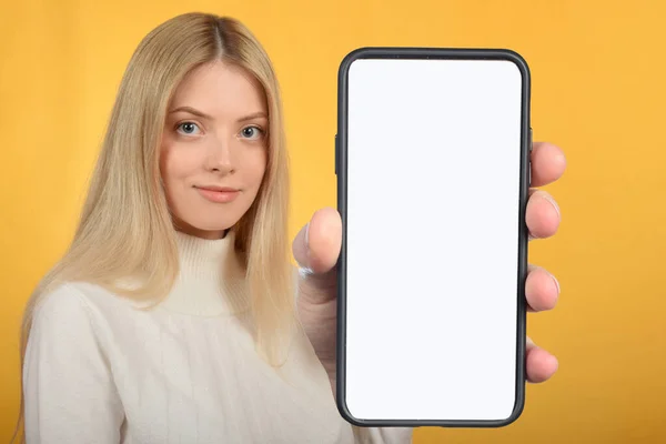 可愛いです可愛いですブロンドの女性白い空白の画面でスマートフォンを示す — ストック写真