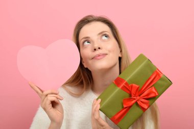 Hediye kutusu ve renkli bir kalbi olan genç bir kadın. Sevgililer Günü kutlaması