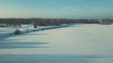 Sunny Winter Afternoon 'da Parktan Donmuş Nehre İHA uçuyor. Sinema Drone Kış Görüntüleri. Kar ve Güneş