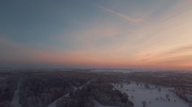 İHA havada uçuyor. Panoramik Şehir ve Park Manzarası Kış Akşamı Günbatımında. Sinema Drone Kış Görüntüleri. Kar ve Güneş. Evler ve Alanlar
