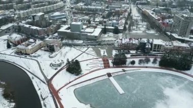 Drone Winter Görüntüleri. Şehir merkezinde donmuş bir göl. Yakınında bir nehir var. Sinema Drone Kış Görüntüleri. Kar, Buz, Donmuş Göl, Bulutlar. Evler ve Sokaklar.