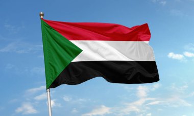 Sudan bayrağı rüzgarda dalgalanıyor, kırmızı, beyaz, siyah çizgiler ve kaldırma tarafında yeşil bir üçgen var.