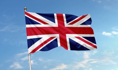 Birleşik Krallık bayrağı, Union Jack olarak bilinir, simgesel kırmızı, beyaz ve mavi çapraz deseni ile açık bir gökyüzü altında dalgalanır.