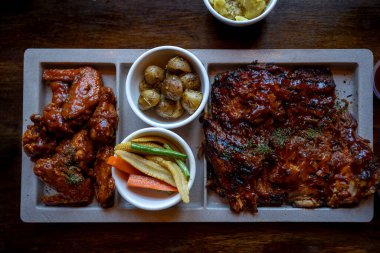 Bufalo kanatları ve patates ve sebzelerle servis edilen kaburga pirzolası ziyafeti..