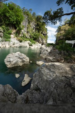 Turkuaz nehri, Minalungao Ulusal Parkı, Nueva Ecija, Filipinler 'deki yüksek kireçtaşı kayalıklarından ve yemyeşil alanlardan geçiyor..