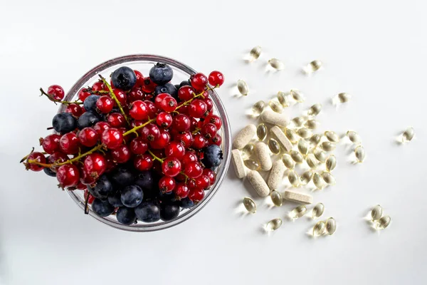 Olgun böğürtlenli cam kase ve çeşitli D vitaminleri.