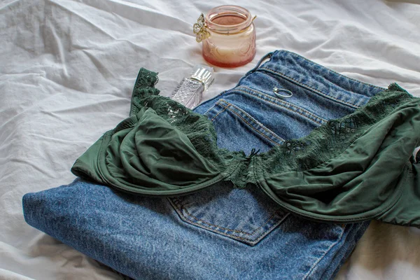 Women's green bra and jeans on a white sheet