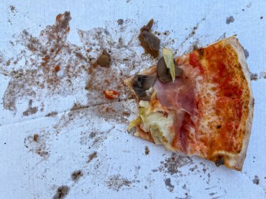 Karton bir kutunun üzerinde son ısırılmış pizza dilimi.