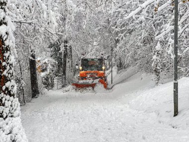 Sarı kar püskürtücü dağ yolunda kar temizliyor.