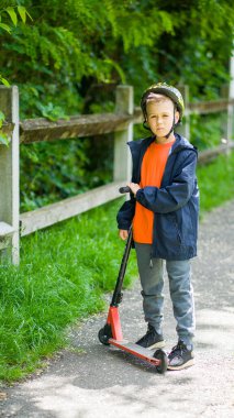 Sarı saçlı ve motosikletli turuncu tişörtlü genç bir çocuk.
