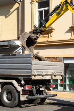 Kazı kovası eski asfaltı kamyon yatağına yığıyor..