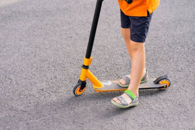 Sarı saçlı ve motosikletli turuncu tişörtlü genç bir çocuk..