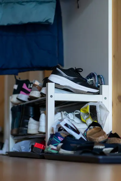 Bir apartman dairesinde çeşitli ayakkabılarla dolu beyaz ayakkabı rafı..
