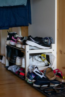 Bir apartman dairesinde çeşitli ayakkabılarla dolu beyaz ayakkabı rafı..