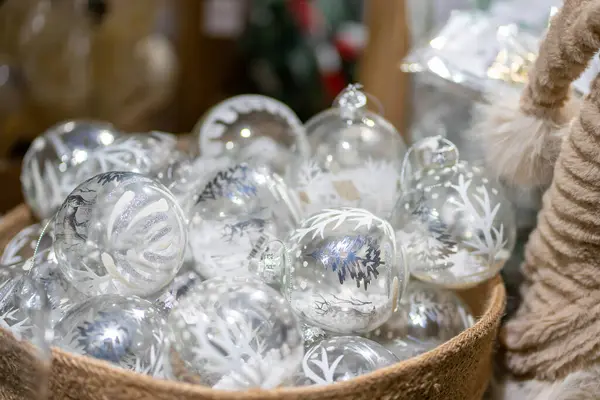 Bej bir tekstil sepetinde saydam cam Noel topları.