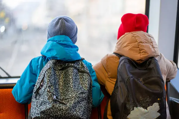 İki okul çocuğu bir tramvayın arka koltuğunda okula gider ve pencereden dışarı bakar..
