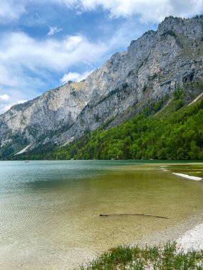 Dağın arka planında yeşil ormanlarla kaplı bir göl..