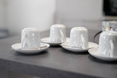 Tepetaklak beyaz porselen bardakların mutfak masasındaki fincan tabakları..