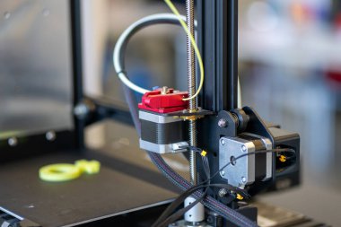 Plastikten yeşil bir sembol basan küçük bir 3D yazıcı.