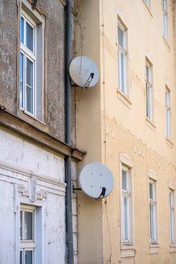 Pencerenin yakınındaki bir binanın duvarına yerleştirilmiş iki uydu anteninin görüntüsü