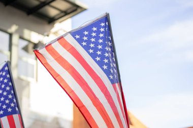 Küçük Amerikan bayraklarını şehirdeki geçit töreninde bir binaya ve gökyüzüne sallarken görüntüsü