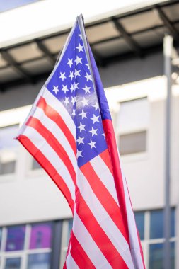 Bir binanın arka planında sallanan küçük bir Amerikan bayrağının görüntüsü.