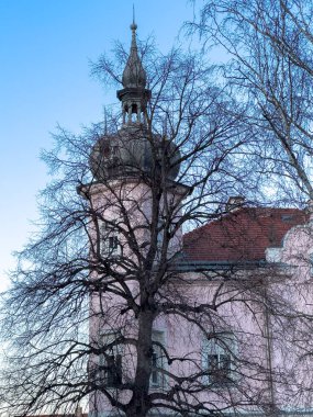 Kışın alacakaranlıkta kulesi olan tarihi bir binanın dış görünüşü.
