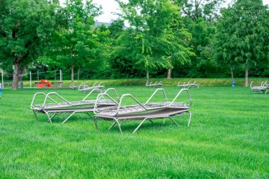 Arka planda şehir parkı olan yeşil bir çayırda üst üste istiflenmiş güneş pansiyonlarının manzarası