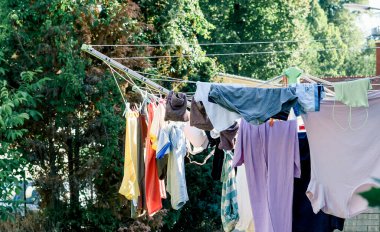 Şemsiye kurutma makinesinde yıkandıktan sonra arka bahçede çeşitli giysiler kuruyor..