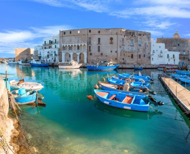 İtalya 'nın güneyindeki Apulia' daki eski Monopoli limanı: balıkçı tekneleri ve kürek çeken eski kasabanın manzarası.