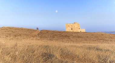 Apulia 'yı keşfeden: İtalya' da Torre Guaceto 'nun Doğa Rezervi. Arka planda gözetleme kulesi ve birkaç bisikletli turist.