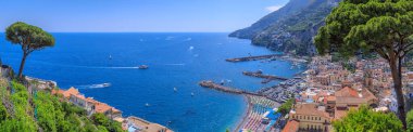  İtalya 'nın Campania bölgesindeki Amalfi kasabası: turistik limanı olan kumlu sahil manzarası ve ikonik bir katedral çan kulesi olan tarihi merkez.