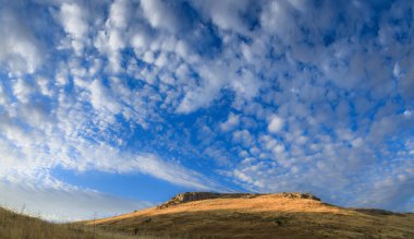 Mavi gökyüzü ve bulutların hakim olduğu tepe tepesi: Apulia, İtalya 'daki Alta Murgia Ulusal Parkı.