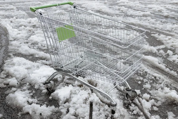 Empty shopping cart in the snow. An abandoned shopping trolley in the snow.